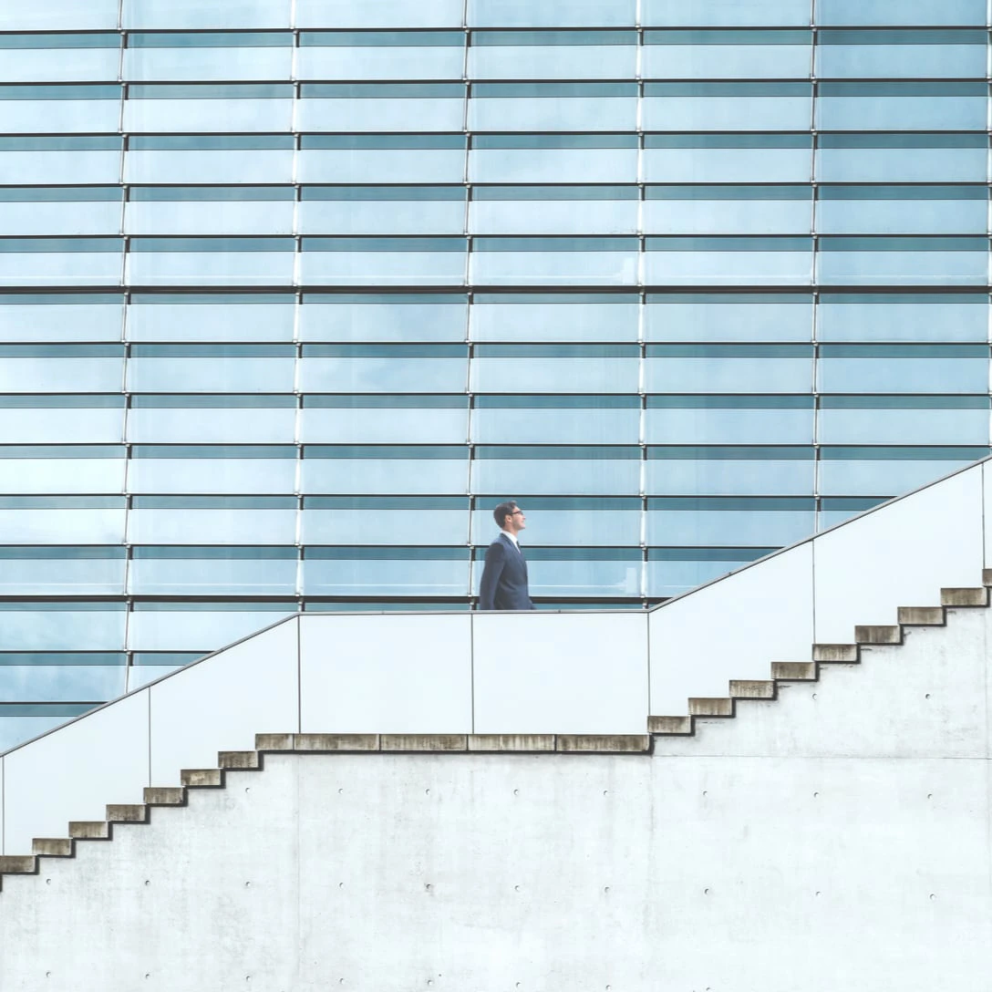 Person steigt vor einem Gebäude die Treppen hoch